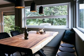 A dining area with a wooden table, black chairs, a bench with cushions, and pendant lights. - Holiday home with 3 bedrooms (Winterberg)