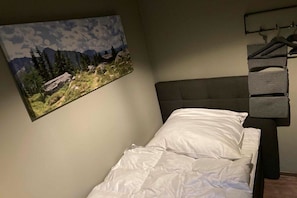 Une chambre à coucher avec un lit, un tableau accroché au mur et un porte-manteau avec des cintres.