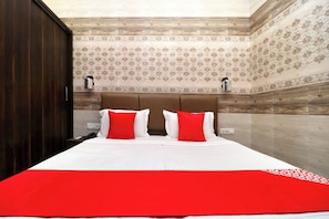 Una habitación de hotel con cama, mesita de noche, teléfono y armario.