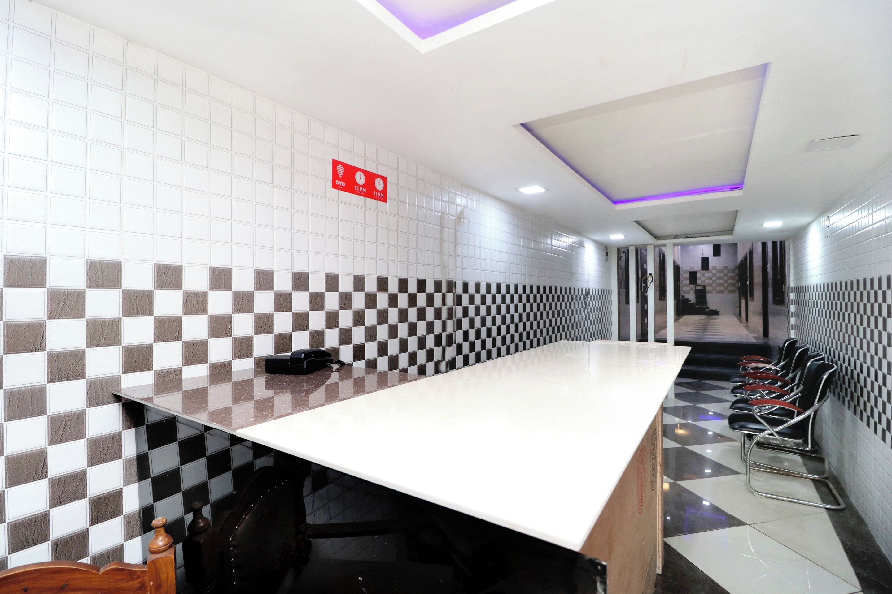 A long counter with a checkered wall pattern, a red emergency exit sign, and a row of chairs along the wall.