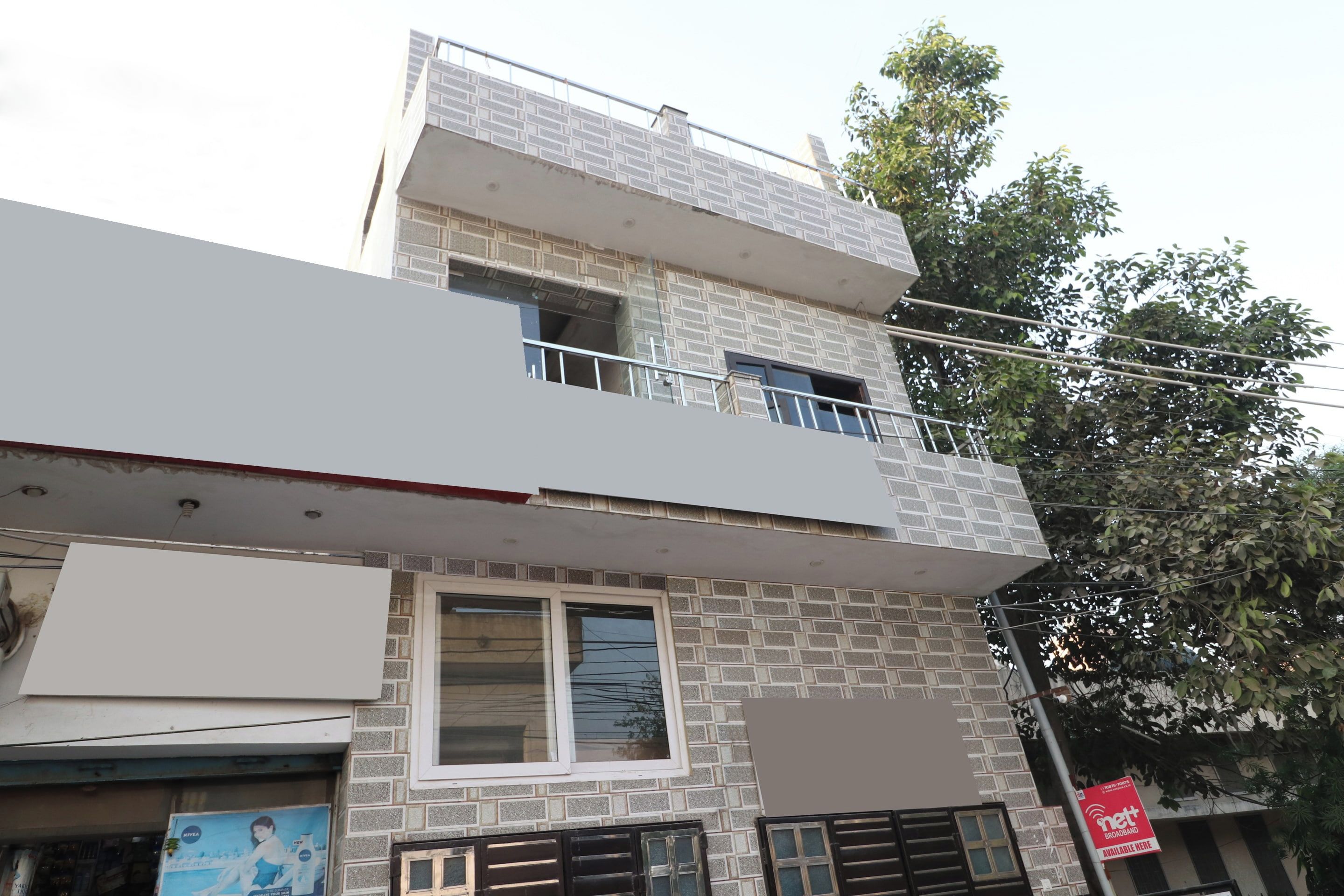 A multi-story building with a balcony on the upper floor, a visible window on the ground floor, and a signboard on the right side.