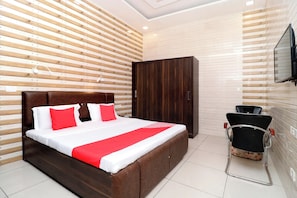 Una habitación de hotel moderna con una cama grande, un armario y un área de descanso.