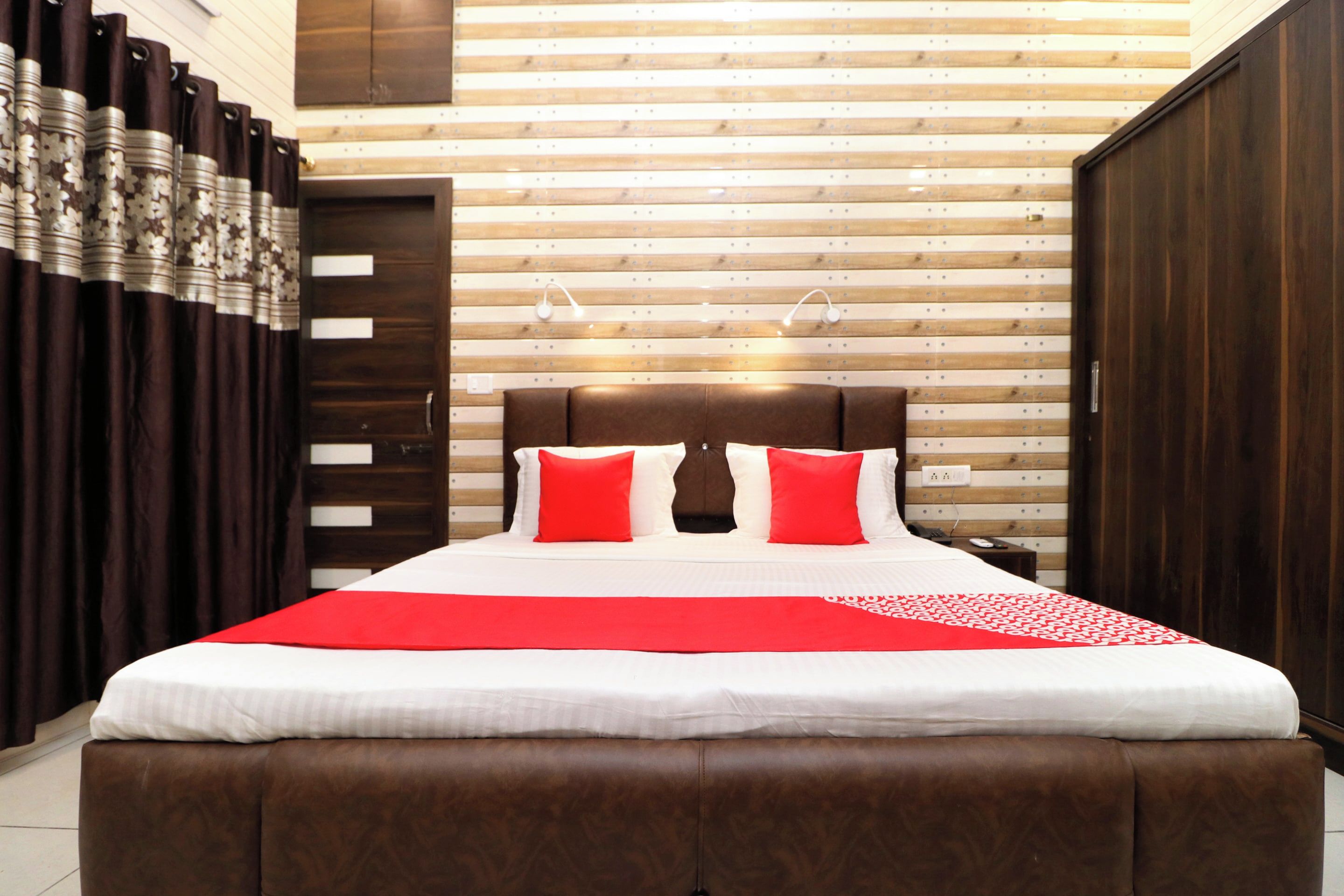 A hotel room with a large bed, a wardrobe, and a wooden slatted wall.