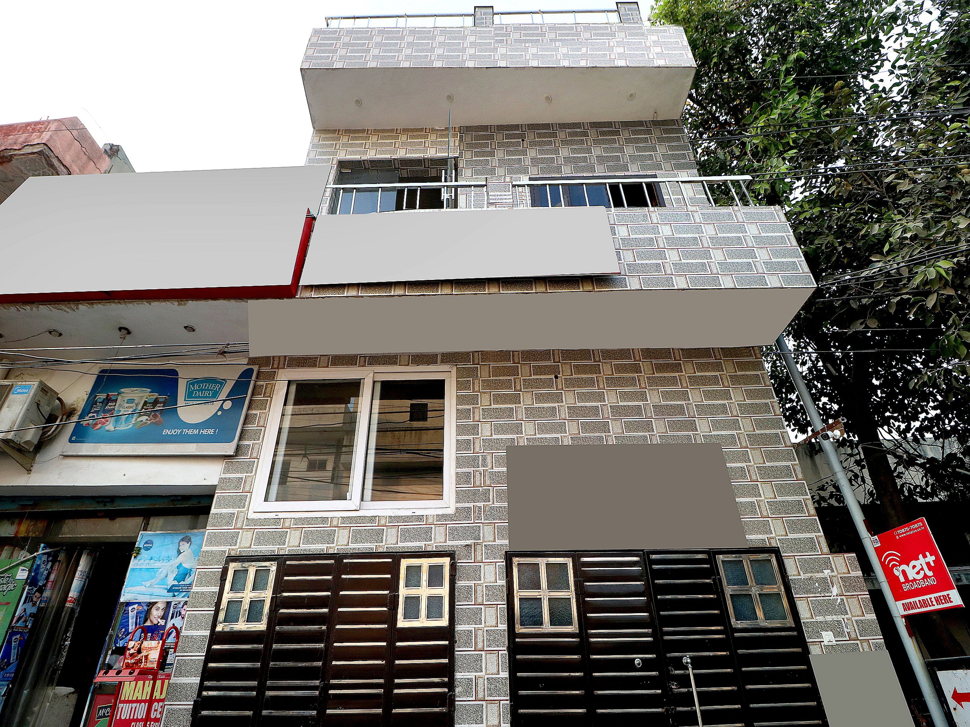 A multi-story building with a brick facade, a visible window, and a signboard advertising broadband services.