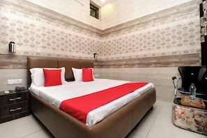 Una habitación de hotel con una cama grande, una mesita de noche, una silla y una pequeña mesa con una botella de agua.