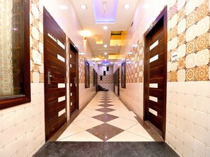 Un pasillo de hotel con paredes estampadas, puertas de madera y suelo de baldosas.