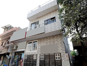 A multi-story building with a brick facade, a balcony on the upper floor, and a gated entrance. - Hotel O Max (Jalandhar)