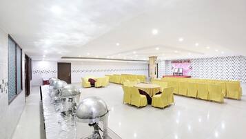 A spacious indoor venue with rows of yellow chairs, a stage, and a water feature.