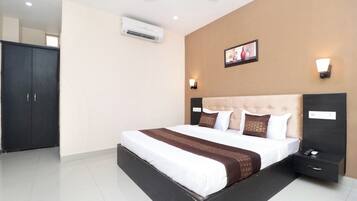 Habitación de hotel con cama, mesitas de noche, equipo de aire acondicionado, ventilador de techo y un cuadro colgado en la pared.