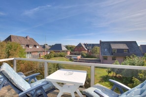 A balcony with a table and chairs, overlooking a residential area with houses and a clear sky. - Holiday apartment in Sylt with 1 bedroom (Wenningstedt)