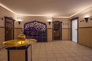 A hotel lobby with a patterned floor, a decorative wall with a floral motif, and a golden table centerpiece. - Holiday apartment in Sylt with 1 bedroom (Wenningstedt)