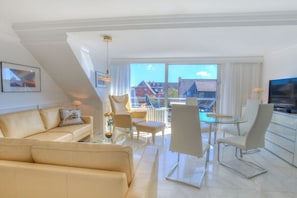 A modern living room with a sofa, chairs, a glass table, and a TV. - Holiday apartment in Sylt with 1 bedroom (Wenningstedt)