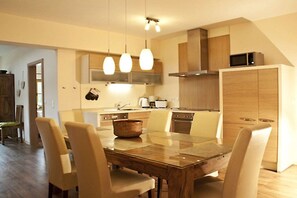 A modern kitchen with wooden cabinets, a dining table, and chairs. - Holiday apartment with 2 bedrooms (Bodenmais)