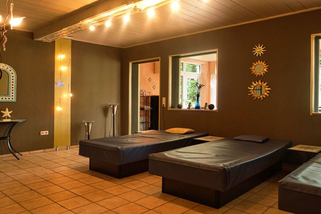 A room with three beds, a mirror, and a small table.