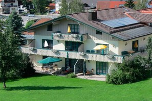 Ein zweistöckiges Gebäude mit Balkon, Außenbereich und einer Solaranlage auf dem Dach.