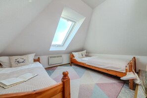 A bedroom with two single beds, a skylight, and a radiator. - Holiday apartment with 1 bedroom (Fehmarn)