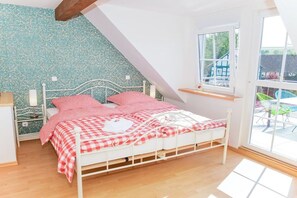 Een slaapkamer met een bed, nachtkastje, raam en uitzicht.