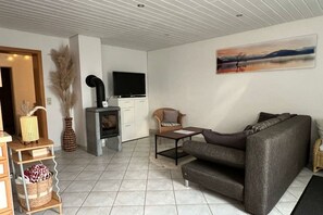 Ein Wohnzimmer mit Sofa, Fernseher, Kamin und einem Bild an der Wand.