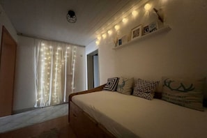 A bedroom with a bed, curtains, a shelf with items, and a ceiling light. - Holiday apartment with 2 bedrooms (Tettnang)