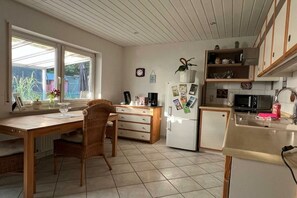 Eine Küche mit Esstisch, Stühlen, einem Kühlschrank, einer Mikrowelle und einem Spülbecken.