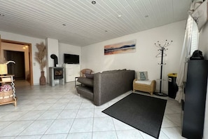 A living room with a grey sofa, a black rug, a fireplace, and a painting on the wall. - Holiday apartment with 2 bedrooms (Tettnang)