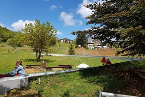 A park with picnic tables, a playground, and a building in the background. - Holiday apartment with 2 bedrooms (Kurort Oberwiesenthal)