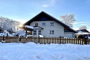 A two-story house with a sloped roof, a wooden fence, and snow on the ground. - Holiday apartment in Monschau-Höfen with Wi-Fi (Monschau-Höfen)