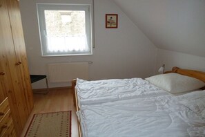 A bedroom with a bed, a window, a radiator, and a wooden wardrobe. - Holiday apartment with 2 bedrooms (Zingst)