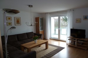 En stue med sofa, sofabord, TV-møbel og en skydedør til en balkon.
