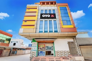 Un edificio de varios pisos con un letrero llamativo para 'OYO Hotel' y 'Tannu Enterprises CCTV'.