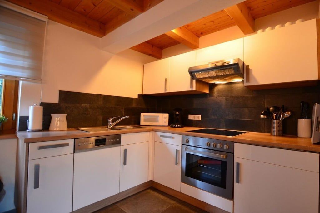 A modern kitchen with white cabinets, a built-in oven, a microwave, and a dishwasher.