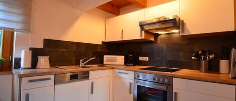 A modern kitchen with white cabinets, a built-in oven, a microwave, and a dishwasher.