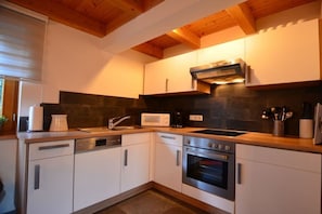 A modern kitchen with white cabinets, a built-in oven, a microwave, and a dishwasher. - Holiday home with 2 bedrooms (Lechbruck am See)
