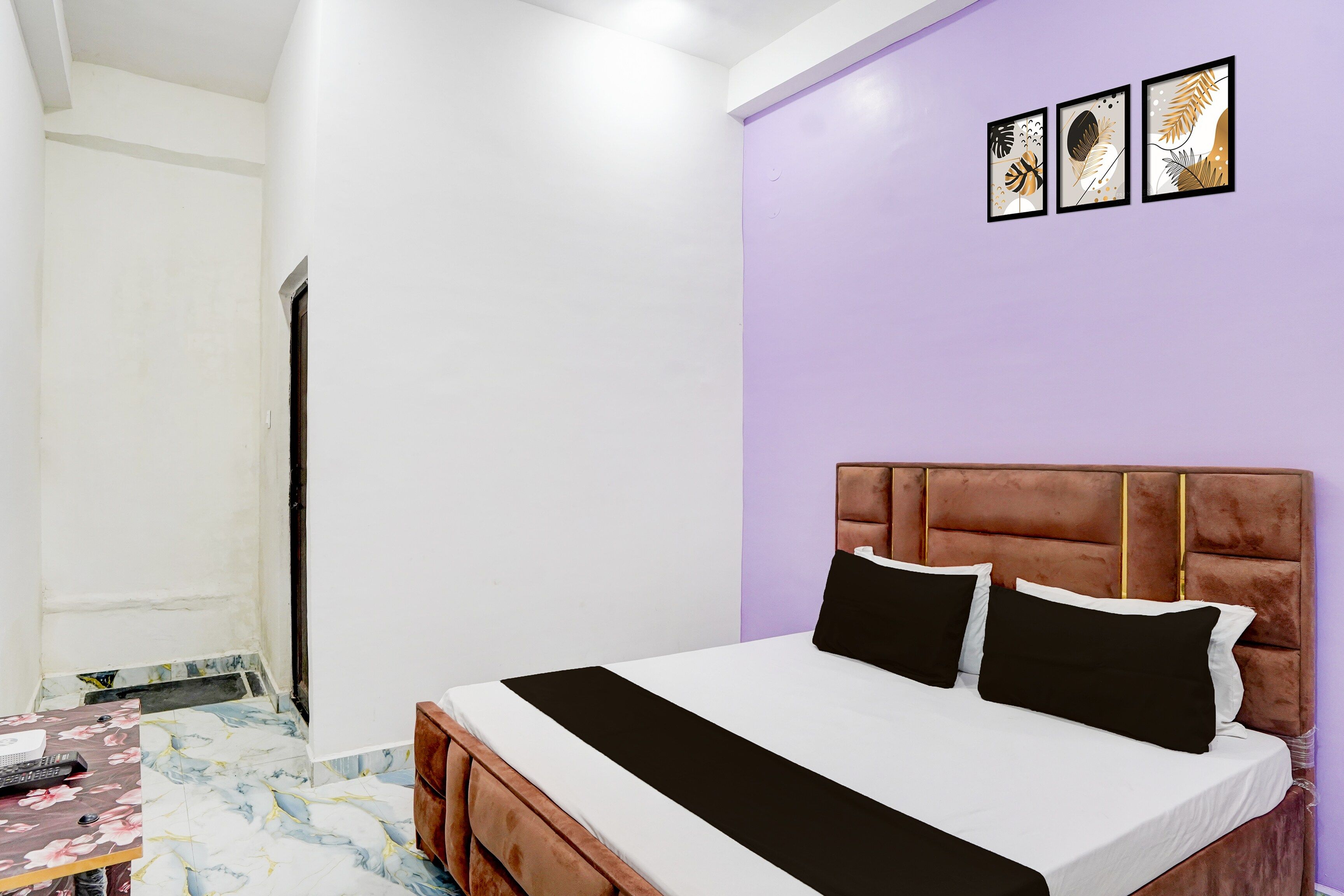 Ein Schlafzimmer mit Bett, Schreibtisch und Stuhl. Eine Tür und eine Wand mit Bildern sind ebenfalls vorhanden.