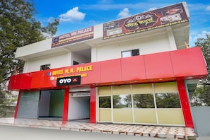 A hotel with a red facade, multiple signs in different languages, and a tiled entrance. - Hotel O MN Palace (Jabalpur)