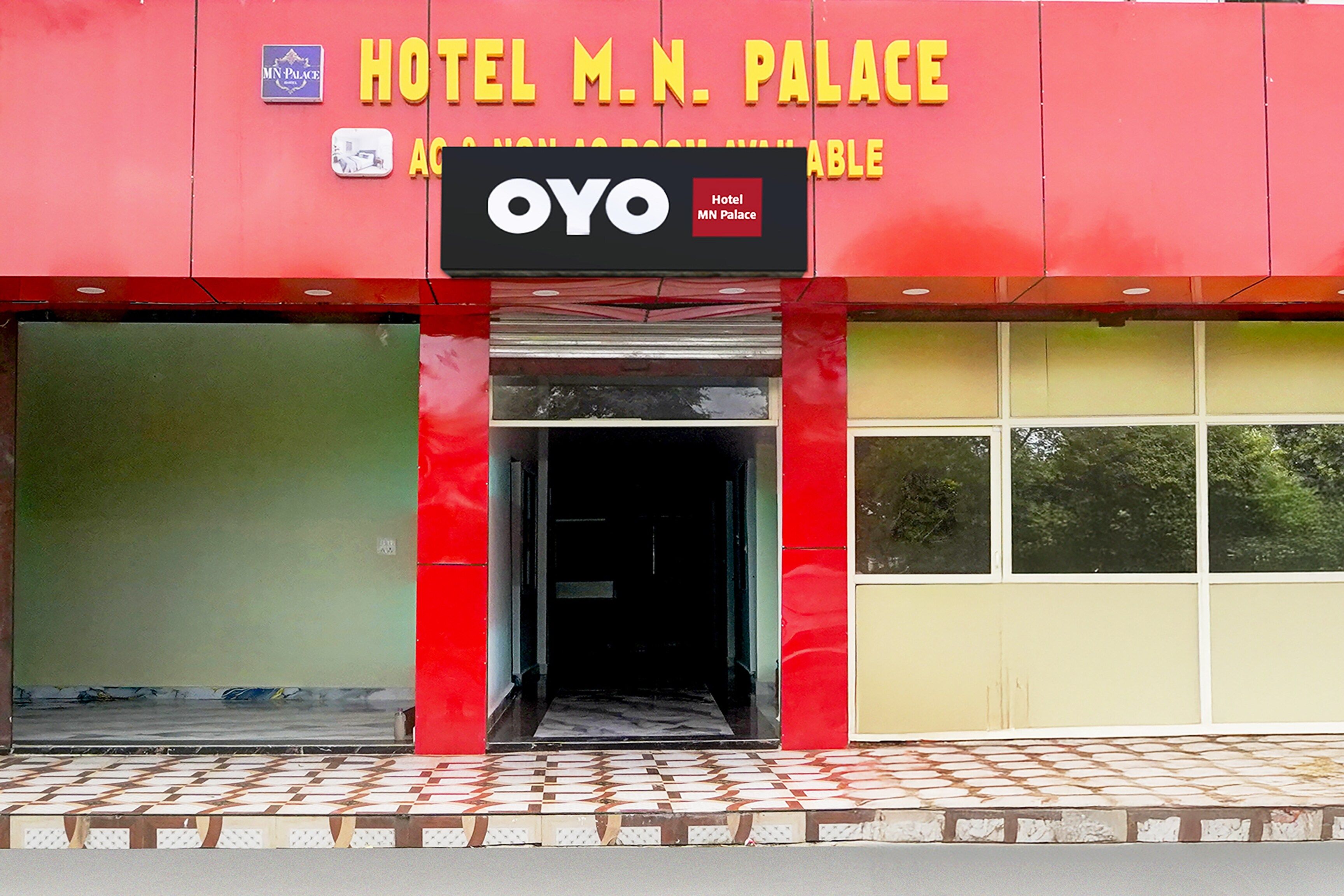 Ein Hotel Eingang mit roter Fassade und einem Schild mit der Aufschrift 'HOTEL M.N. PALACE'.