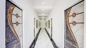 A hallway with marble flooring and doors with decorative metal accents.