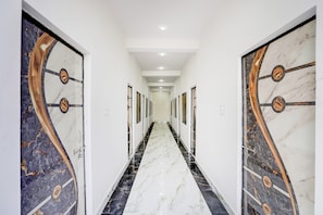 A hallway with marble flooring and doors with decorative metal accents. - Hotel O MN Palace (Jabalpur)