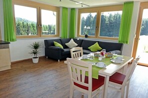 A room with a dining table set for two, a sofa, and a potted plant. - Morning dew on the Florihof (Tennenbronn)