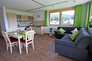 A modern living room with a grey sofa and a dining table with chairs. - Morning dew on the Florihof (Tennenbronn)