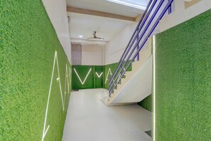 A modern interior with a staircase, green wall accents, and a ceiling fan. - Hotel O City Point (Jabalpur)