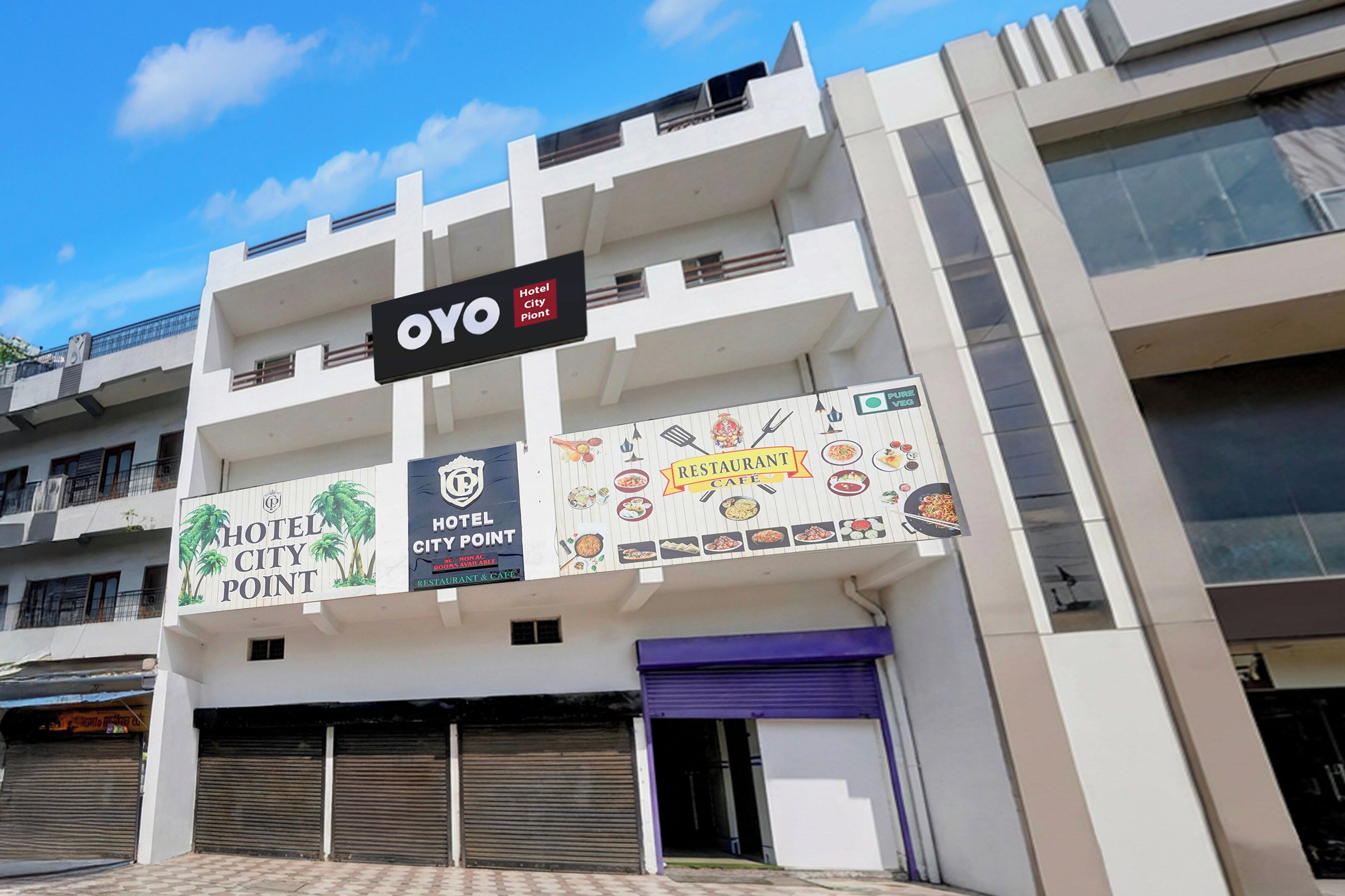 A multi-story building with a sign for 'OYO Hotel City Point' and a banner advertising a restaurant and café.