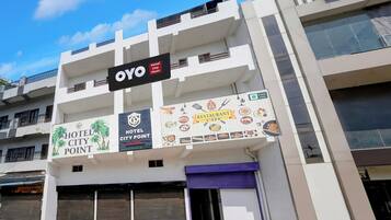 A multi-story building with a sign for 'OYO Hotel City Point' and a banner advertising a restaurant and café.