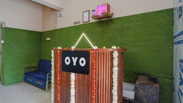 A reception area with a sign reading 'OYO,' a blue seating area, and a green wall.