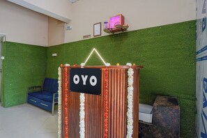 A reception area with a sign reading 'OYO,' a blue seating area, and a green wall. - Hotel O City Point (Jabalpur)
