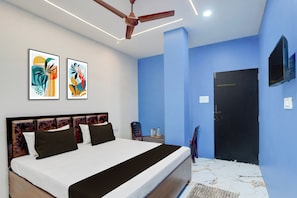 Une chambre à coucher moderne, équipée d’un lit, d’un ventilateur de plafond, d’œuvres d’art et d’un téléviseur fixé au mur.
