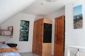 Ein Schlafzimmer mit einem Bett, einem Bücherregal, einem Holzschrank, einer Schiefertafel und einem Gemälde.