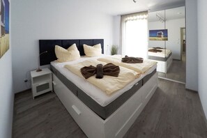 A modern bedroom with a bed, bedside tables, and a large mirror. - Holiday apartment Toplaterne (Dierhagen)