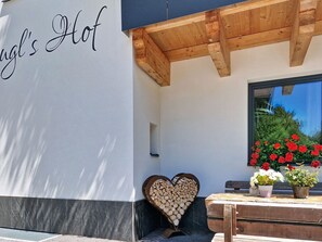 Ein Gebäude mit einer Fassade, einem Schild mit der Aufschrift 'Hof's Hot' und einer Holzbank mit einer herzförmigen Holzscheibe.
