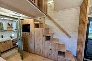 Ein Holzinnenraum mit Küchenzeile, Treppe und integriertem Fernseher.